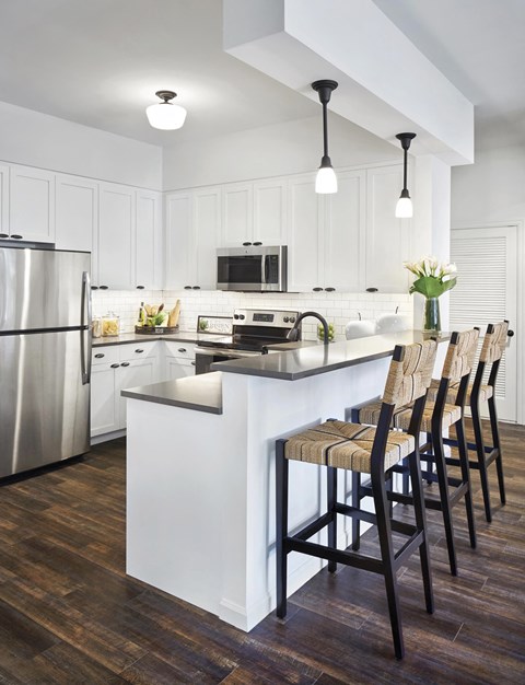 a kitchen with white cabinets and a island with bar stools