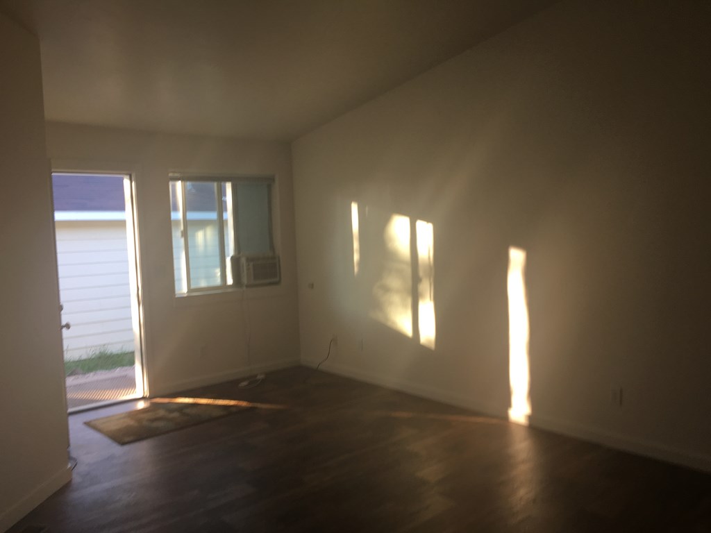 an empty living room with wood floors and a window