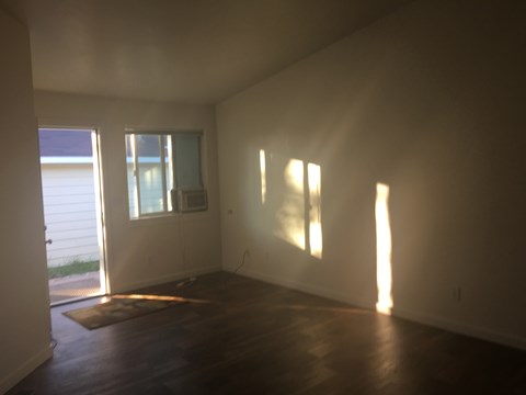an empty living room with wood floors and a window