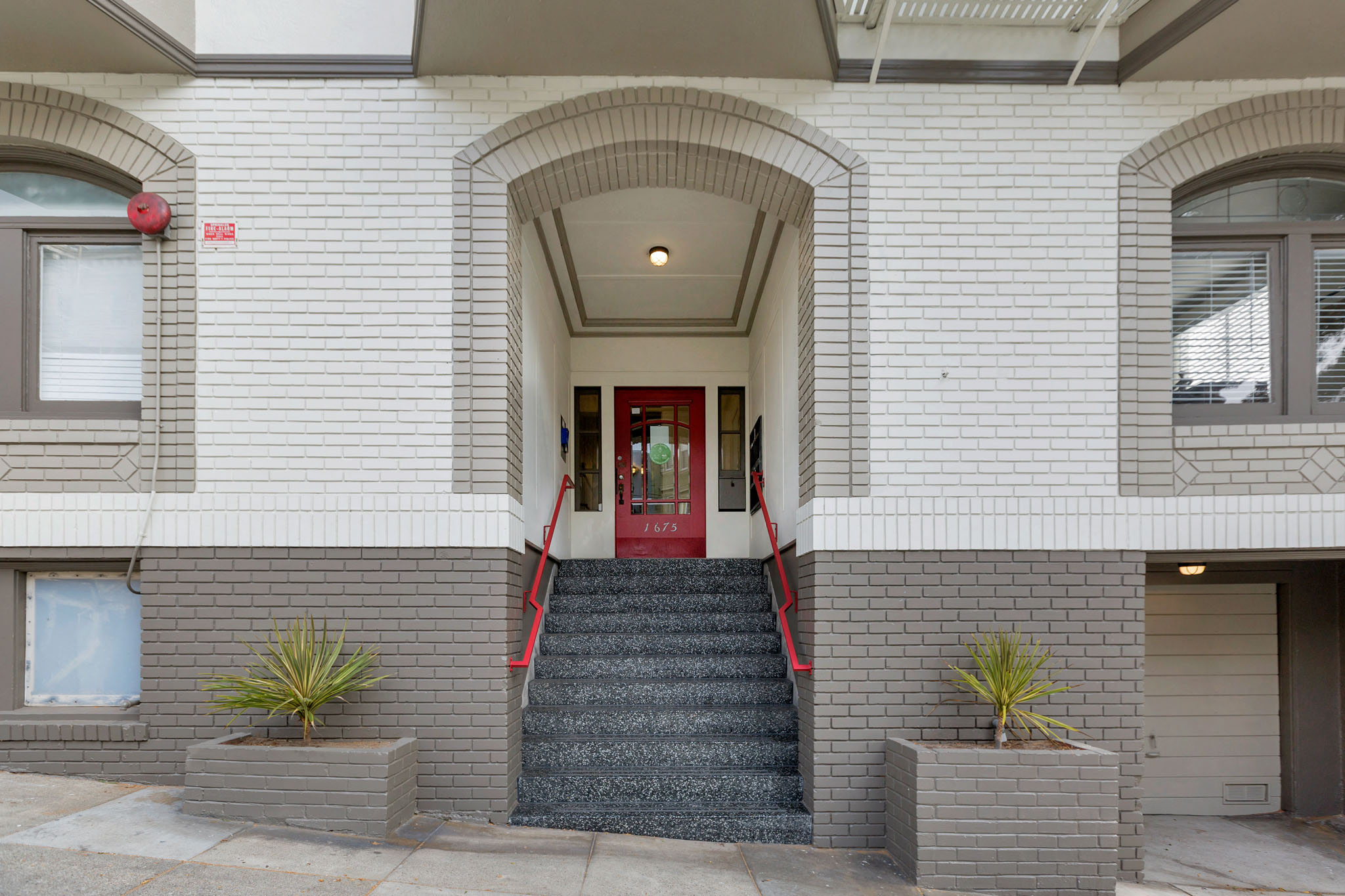 A white building with a red door and steps leading up to it.