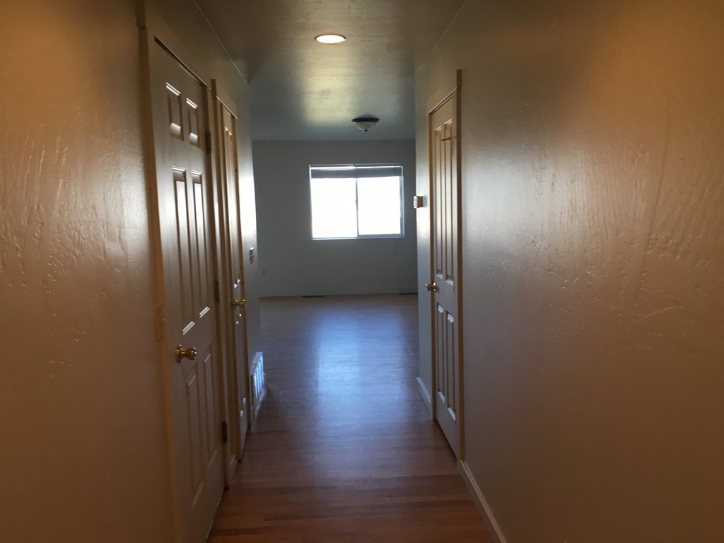 A long hallway with doors on both sides and a window in the middle.