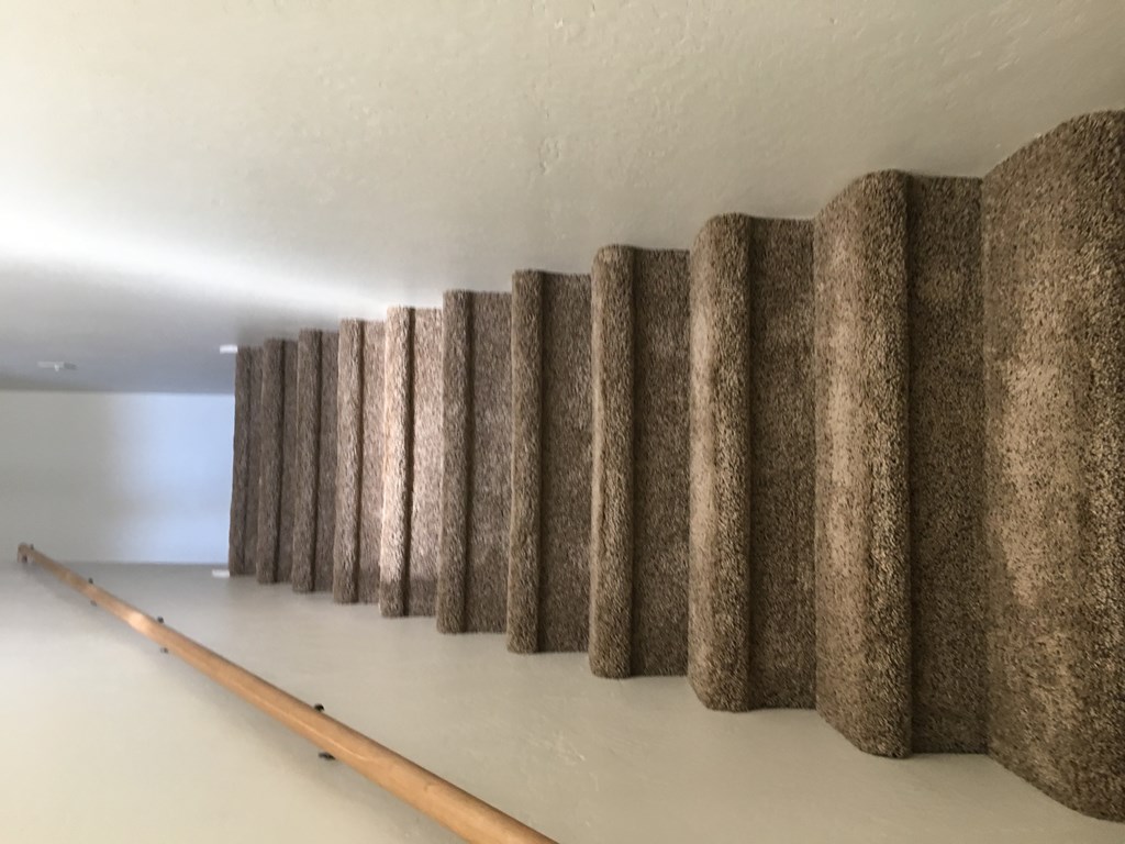 A long row of brown columns are lined up against a white wall.