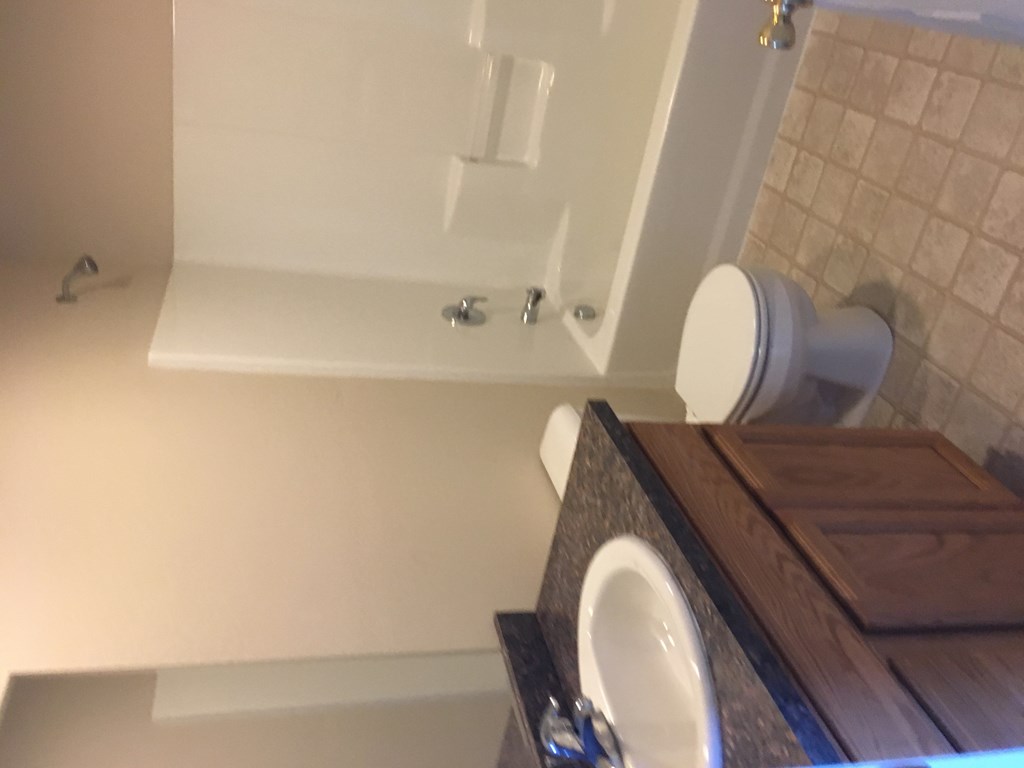 A white bathtub with a white shower head and faucet.