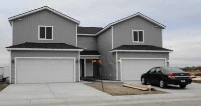A two-story house with a car parked in front.