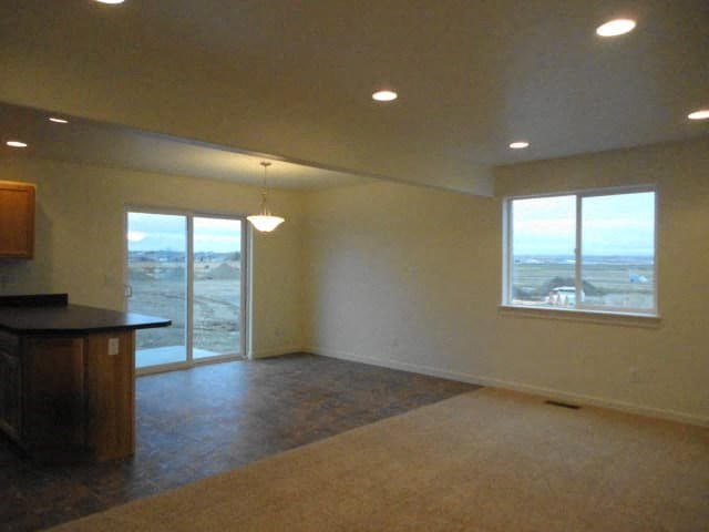 A large empty room with a kitchen area and a view of the outside.