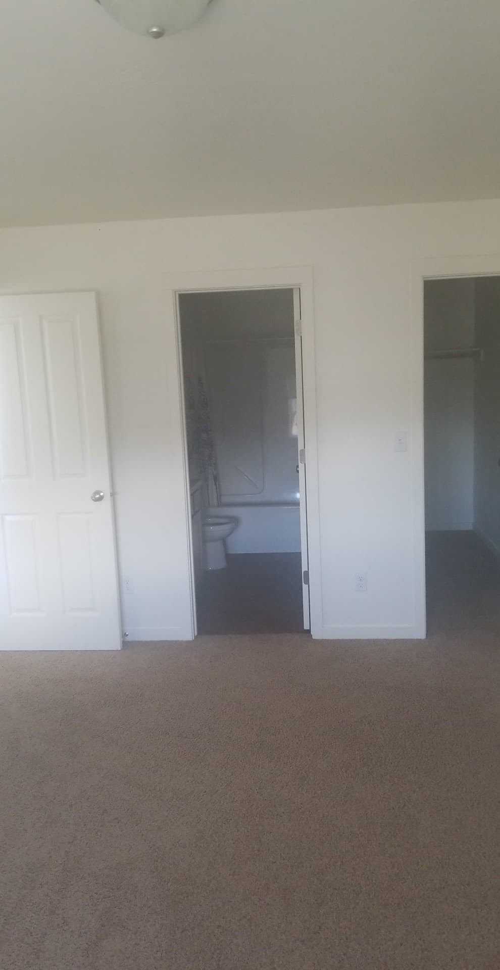 A carpeted room with a doorway leading to another room.