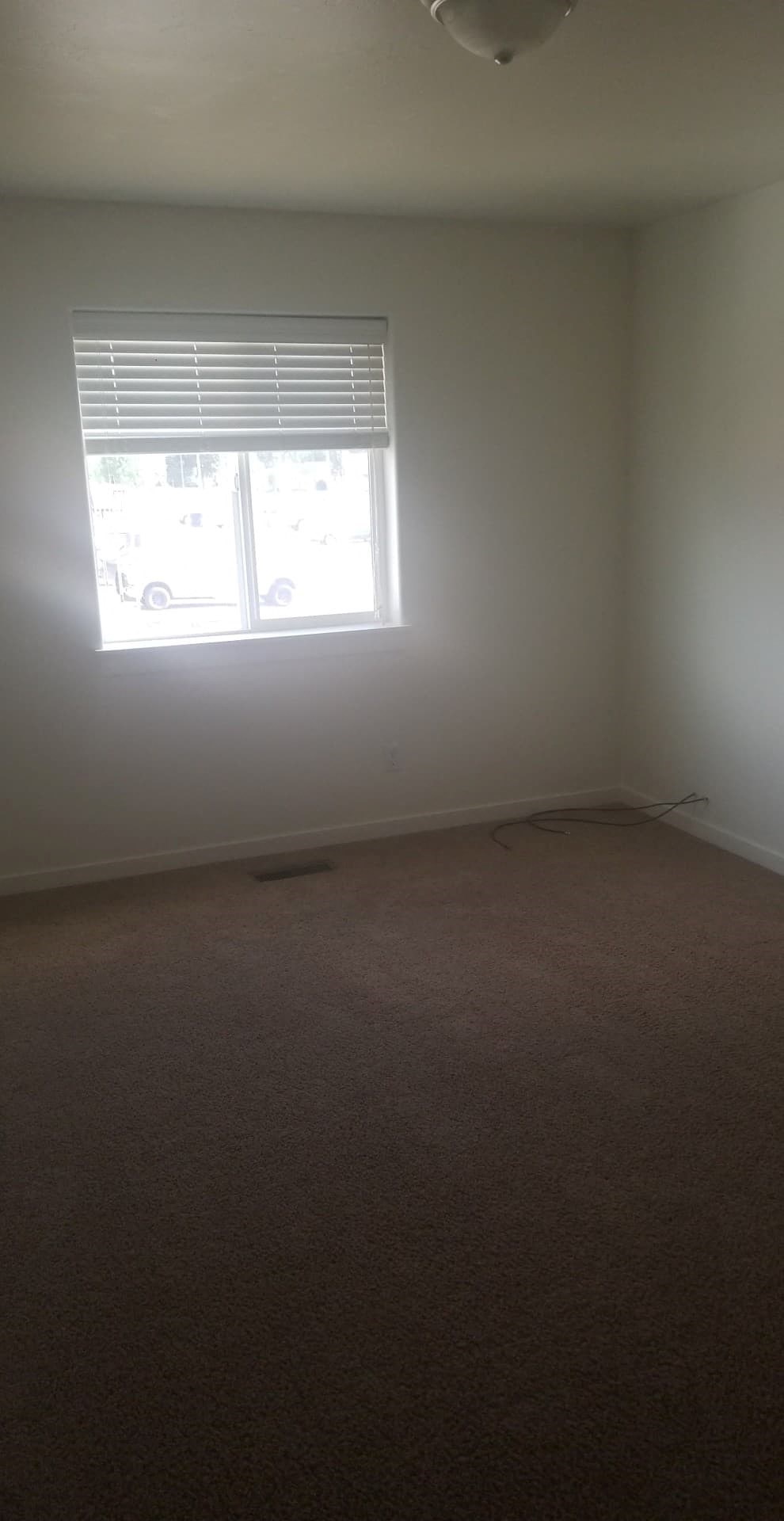 A room with a window and carpet on the floor.