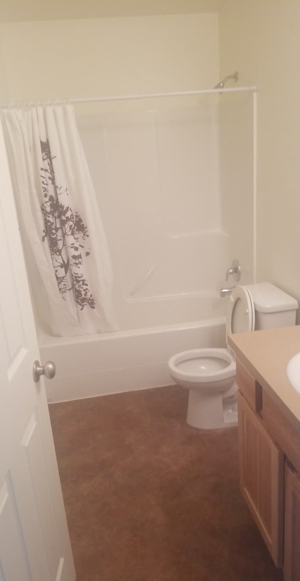 A white toilet sits in a bathroom next to a shower curtain.