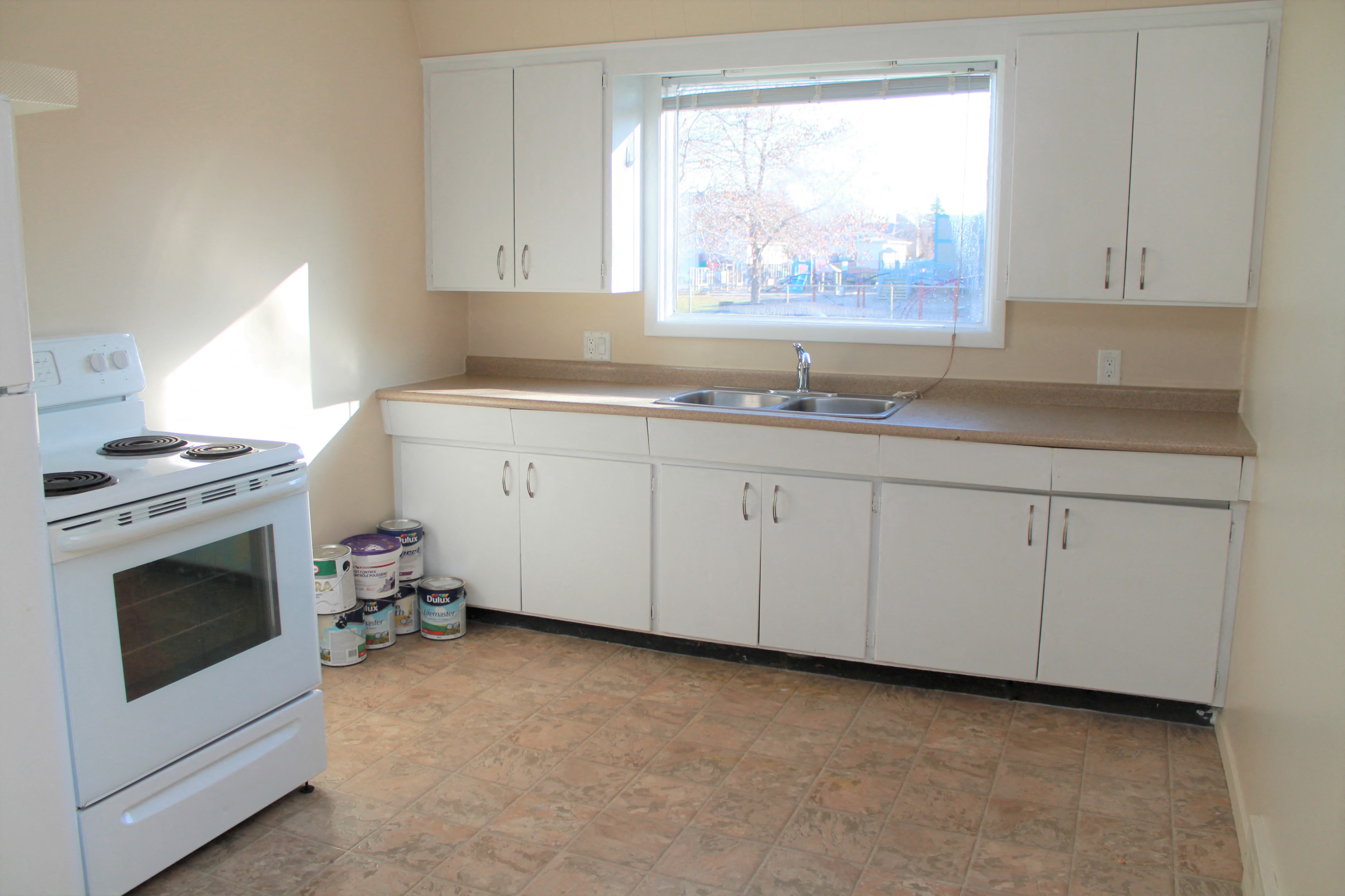 a kitchen with white cabinets and a sink and a window