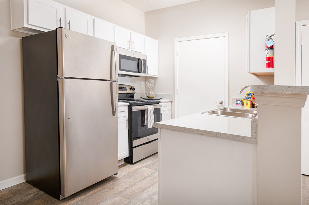 a kitchen with white cabinets and stainless steel appliances and a refrigerator