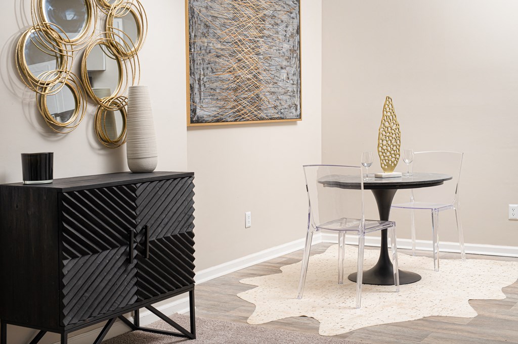 a dining room with a round table and a black and white cabinet with a chair
