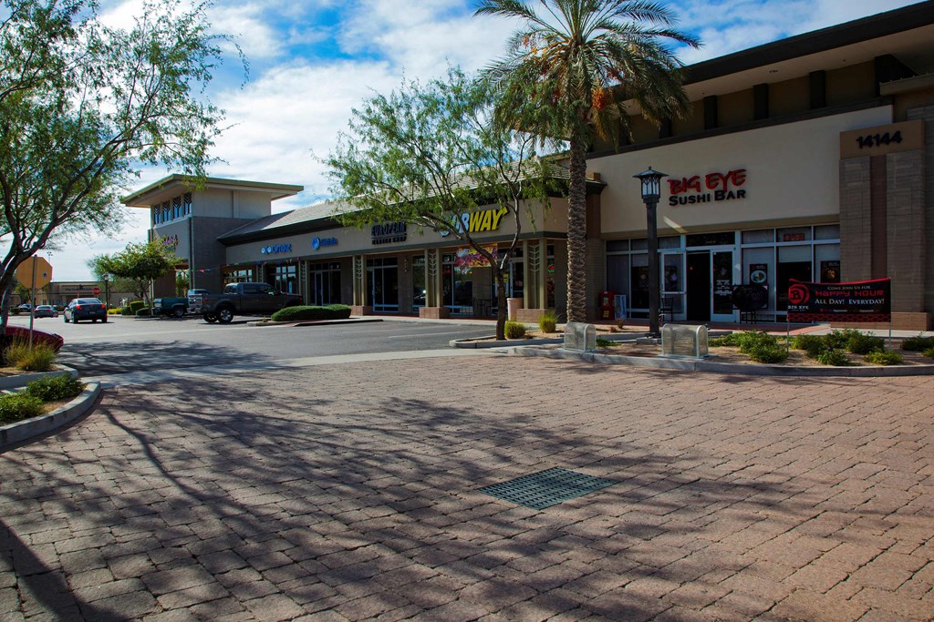 a shopping center with a parking lot and palm trees