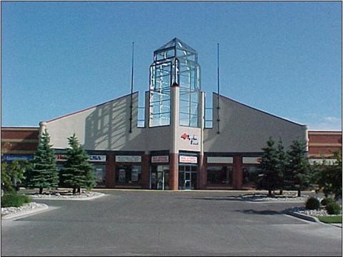 A large building with a glass tower on the left side and a red sign on the right side.