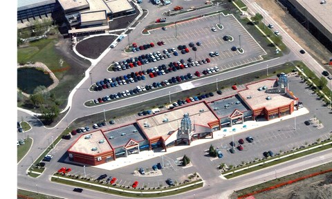 An aerial view of a parking lot with cars and a building with a red roof.