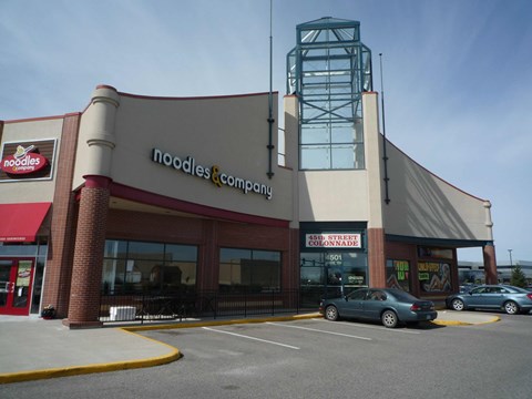 A Noodles & Company restaurant with a car parked in front.