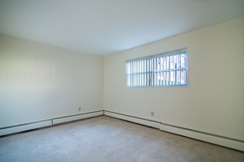 the living room of a home with white walls and a window