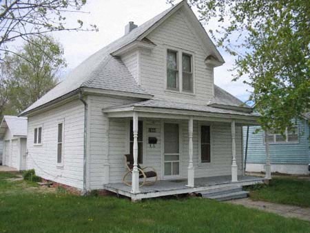 a white house with a porch with a chair on it