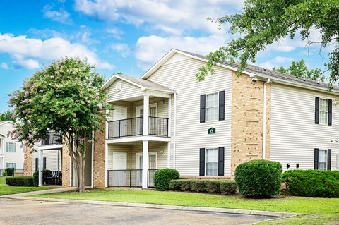 A white apartment building with a green lawn in front.