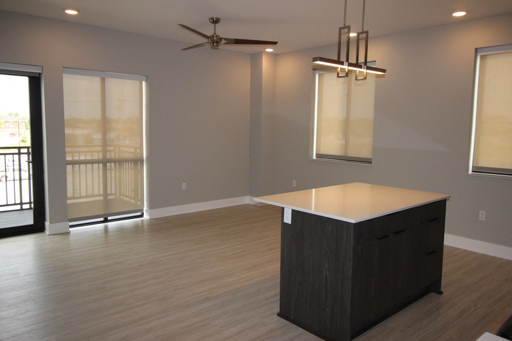 an empty living room with an island and a ceiling fan