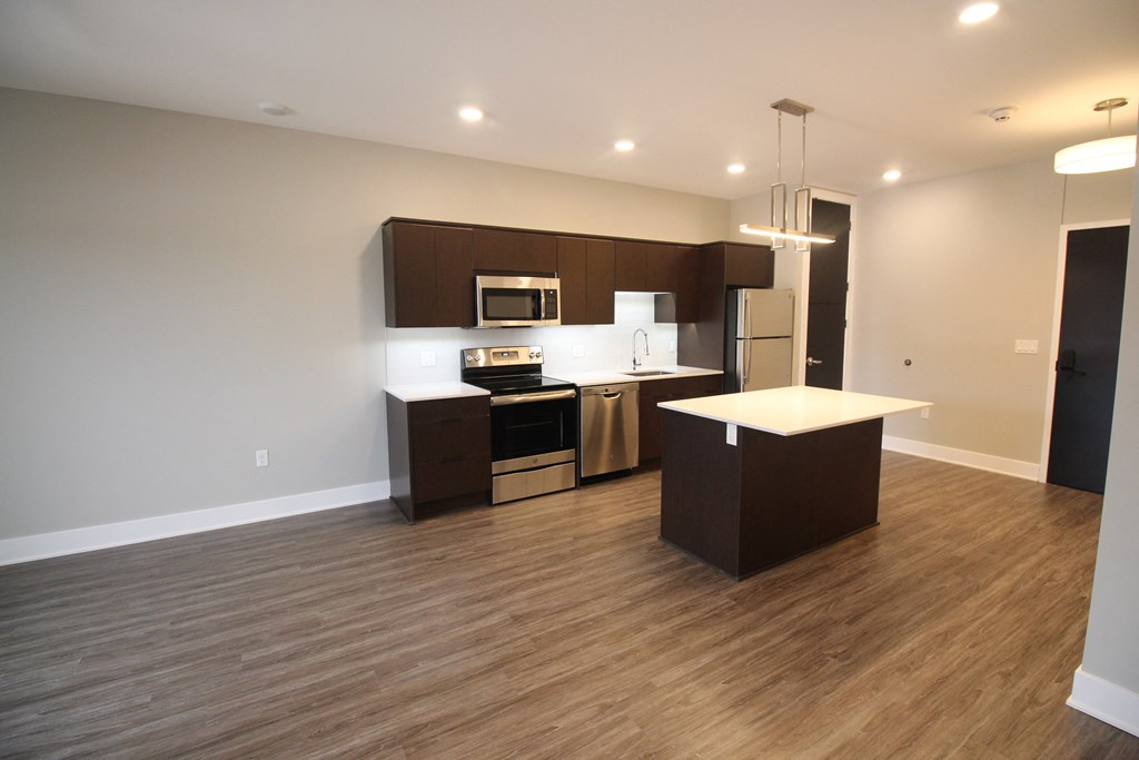 an empty kitchen with wood flooring and stainless steel appliances