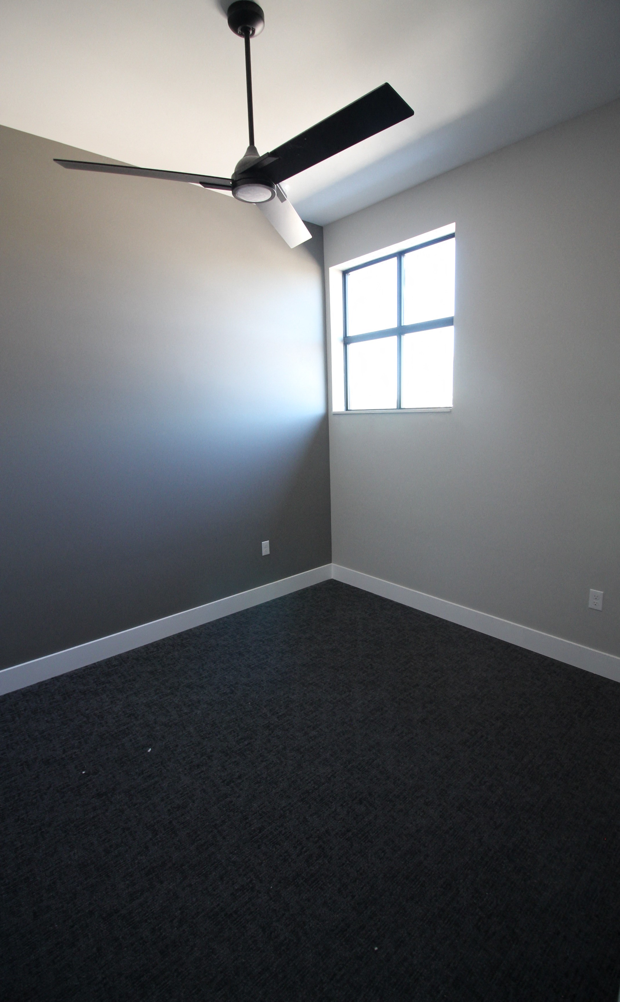 an empty room with a ceiling fan and a window