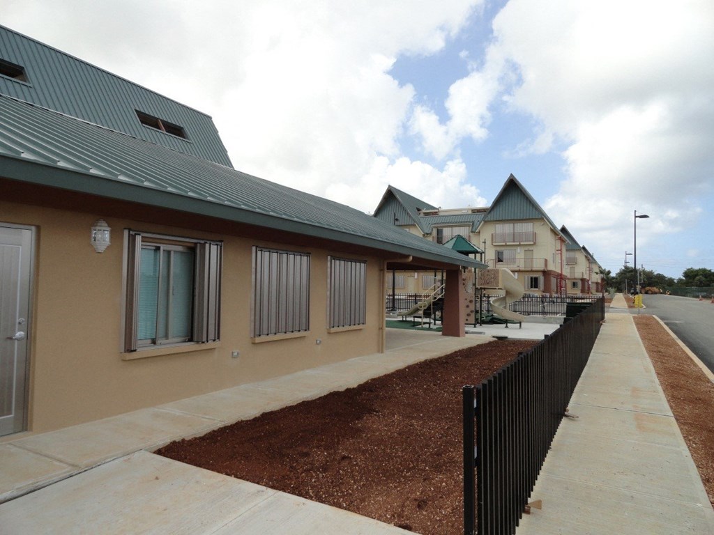 a row of buildings with a sidewalk and a black fence