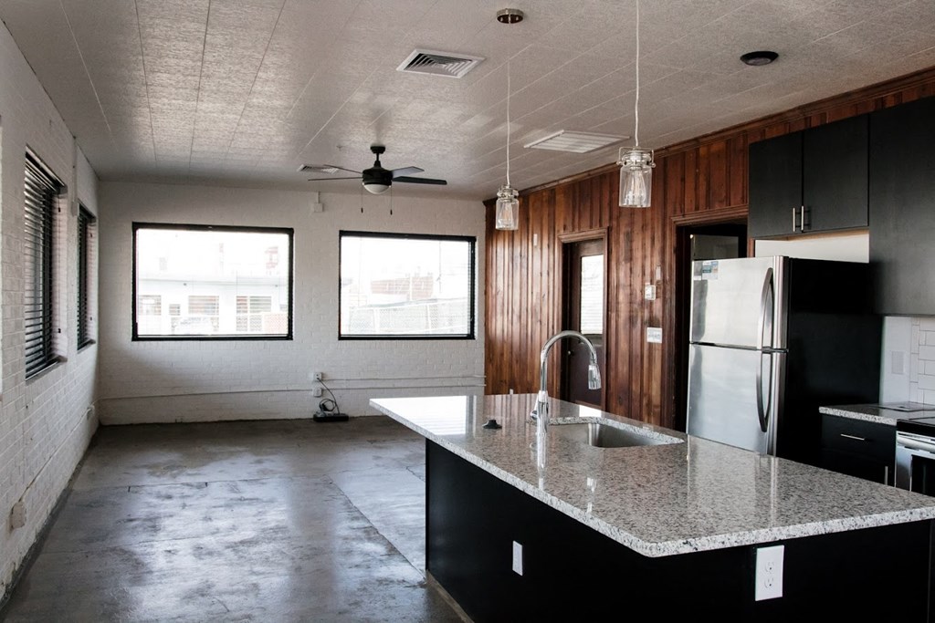 an empty kitchen with a granite counter top and a refrigerator