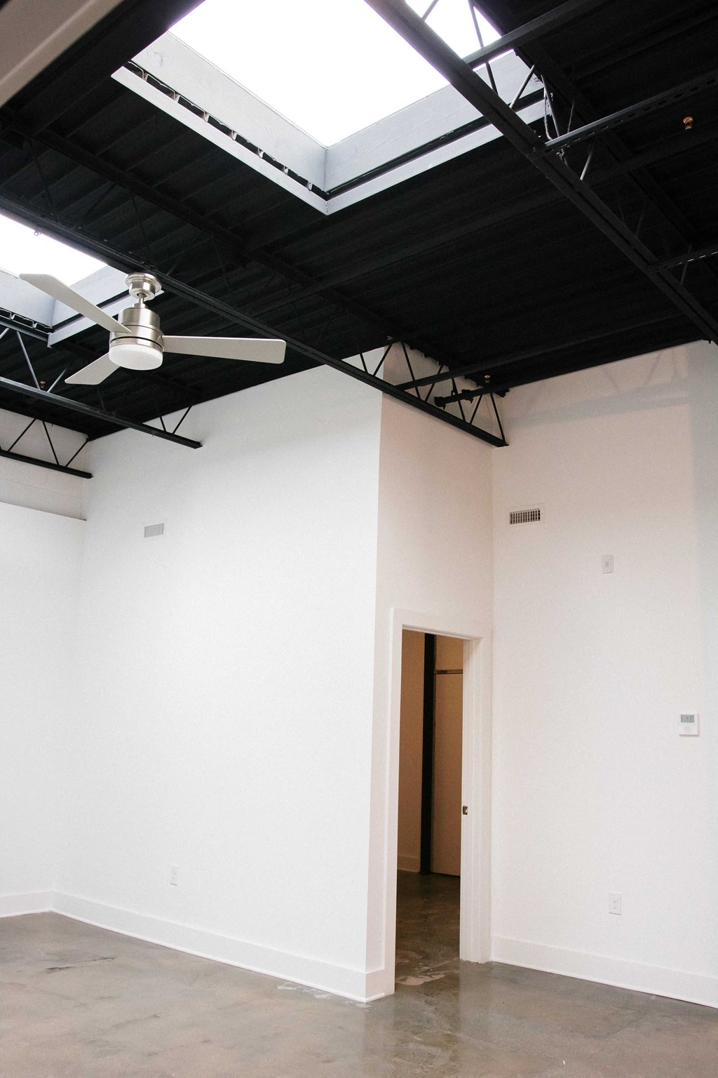 an empty room with white walls and a ceiling fan