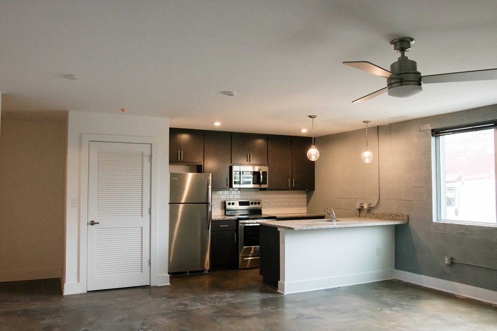 an empty kitchen with stainless steel appliances and a white counter top