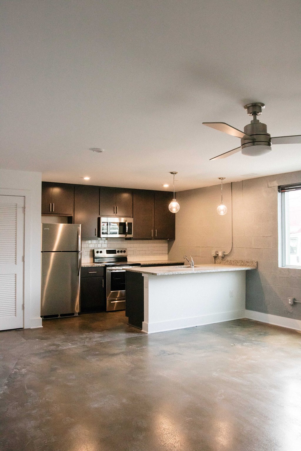 an empty kitchen with stainless steel appliances and a ceiling fan