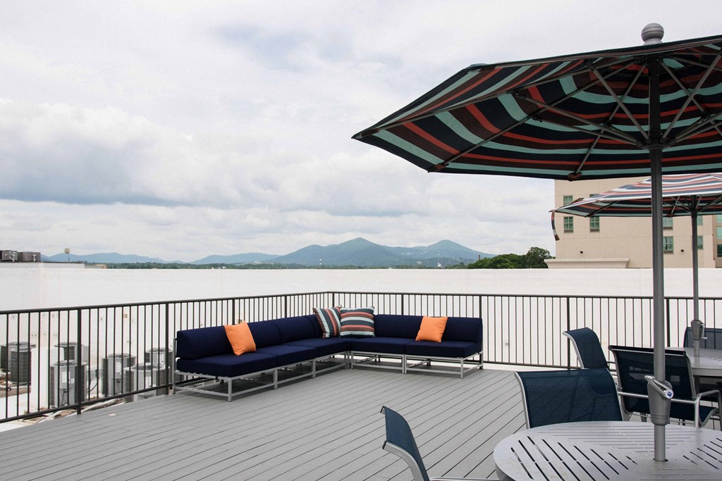 a deck with couches and umbrellas overlooking a body of water