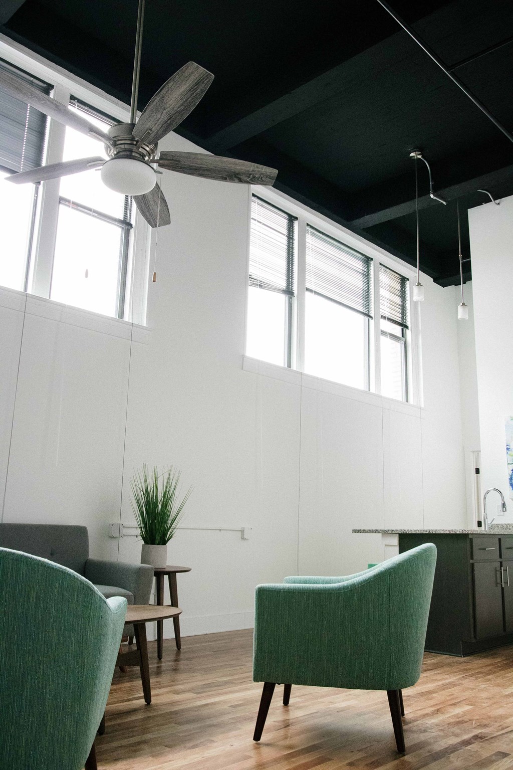 a living room with green chairs and a ceiling fan