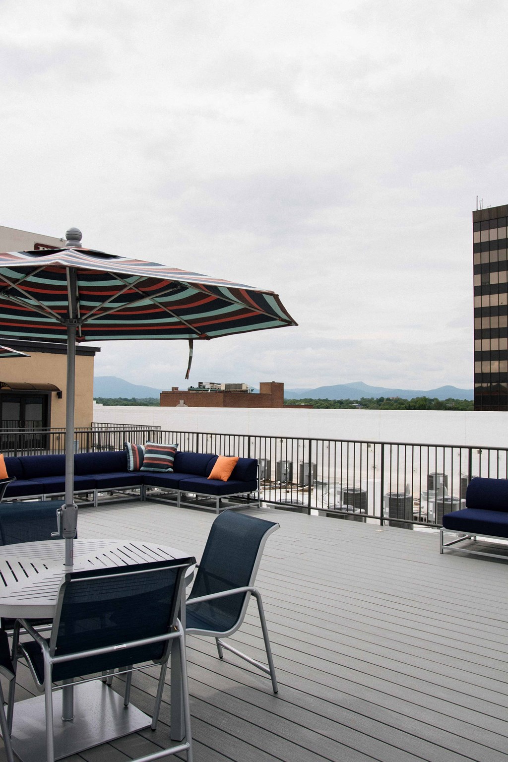 the deck on the top of the building has tables and chairs and an umbrella