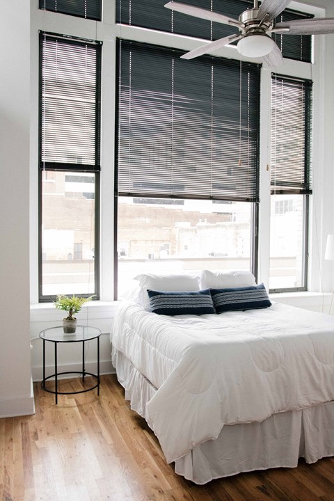 a small bedroom with a bed and large windows