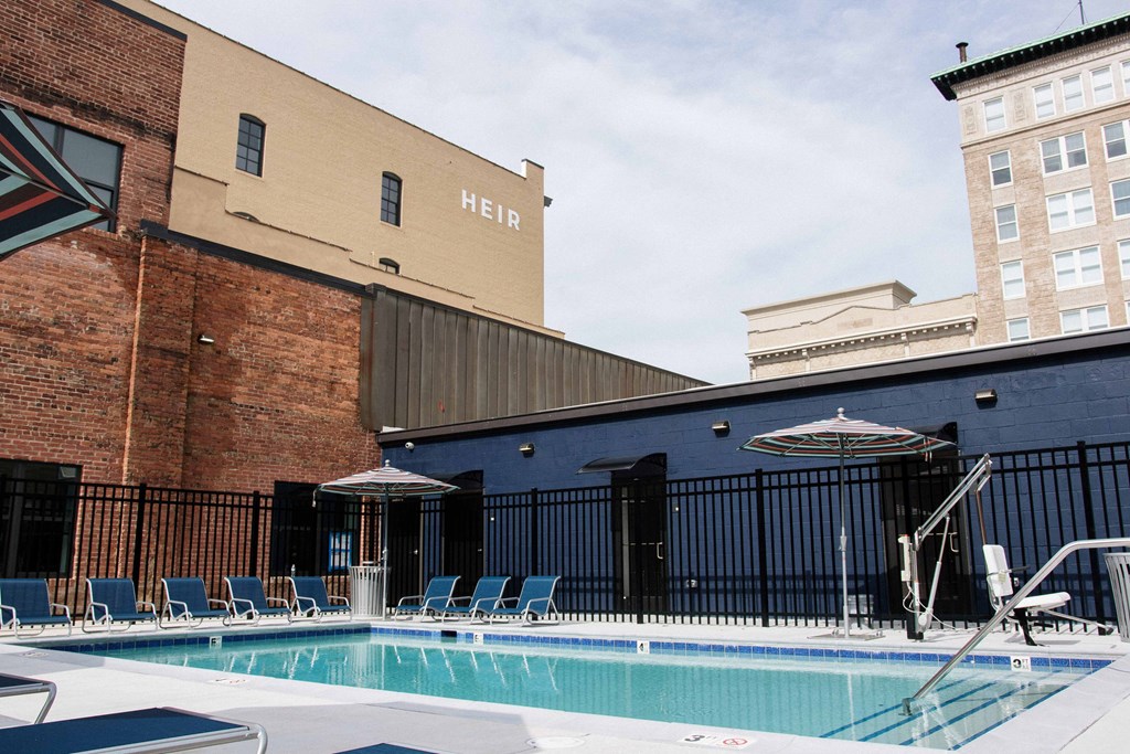 a pool with chairs and umbrellas next to a brick building
