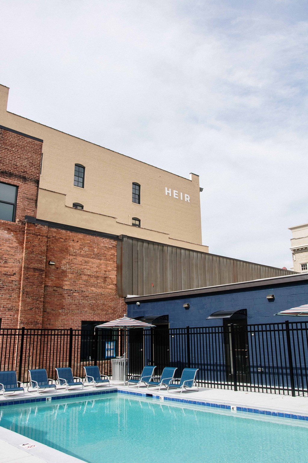 a swimming pool in front of a building with chairs