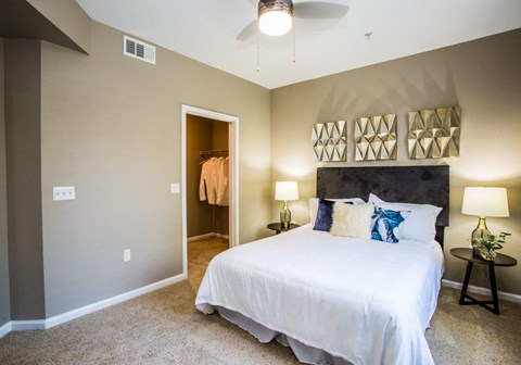 A bedroom with a white bed and a ceiling fan.