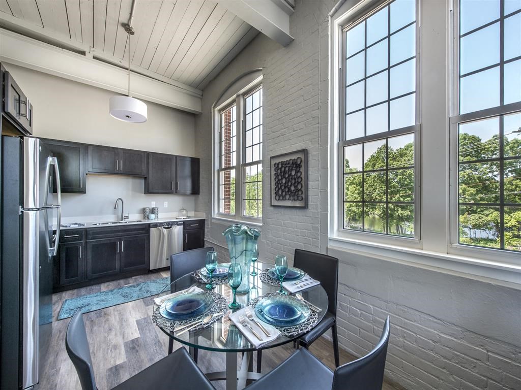 a dining room with a table and chairs and a kitchen with large windows