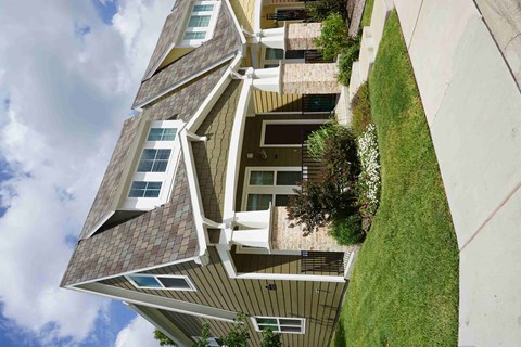 a view from below of a tall apartment building with balconies and green grass