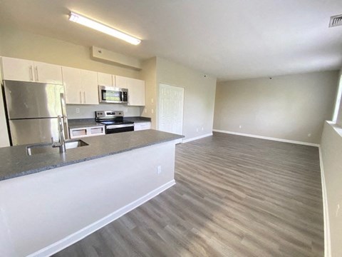 an empty kitchen and living room with wood flooring