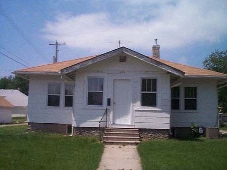 a small white house with a sidewalk in front of it