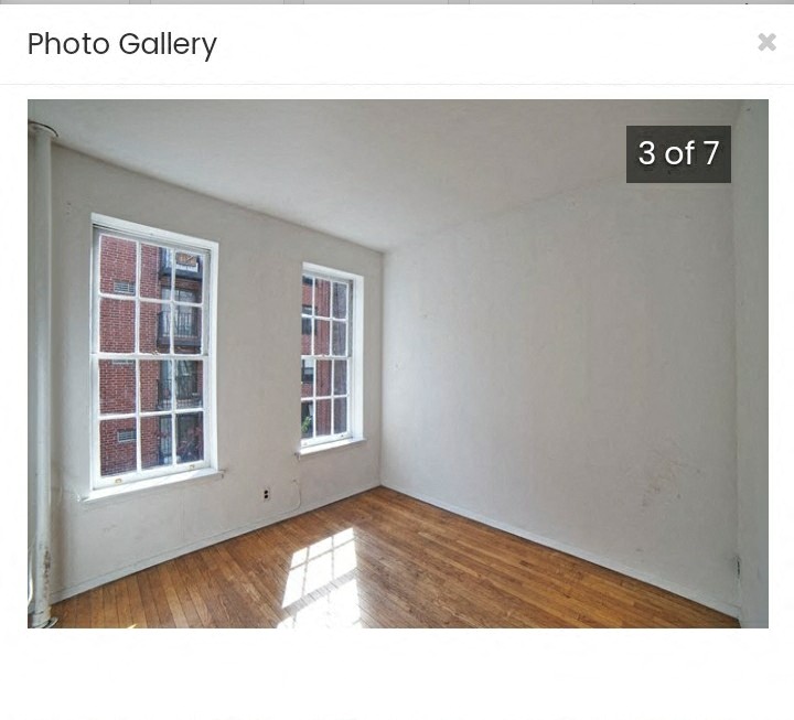 an empty room with a wood floor and two windows