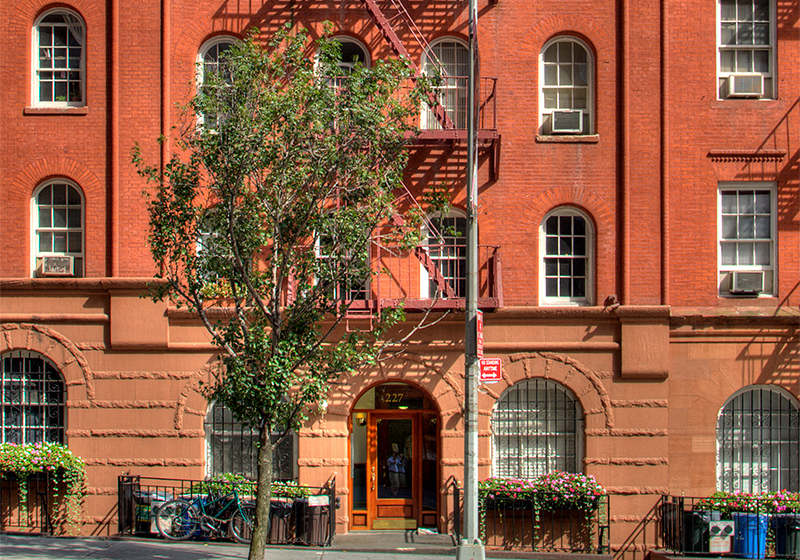 a red brick building with a tree in front of it