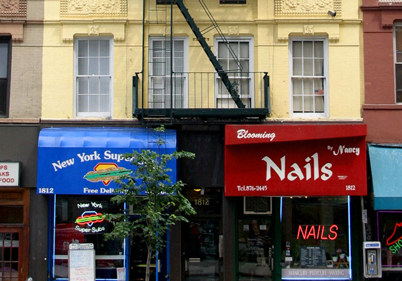 a city street with stores and a building with a fire escape