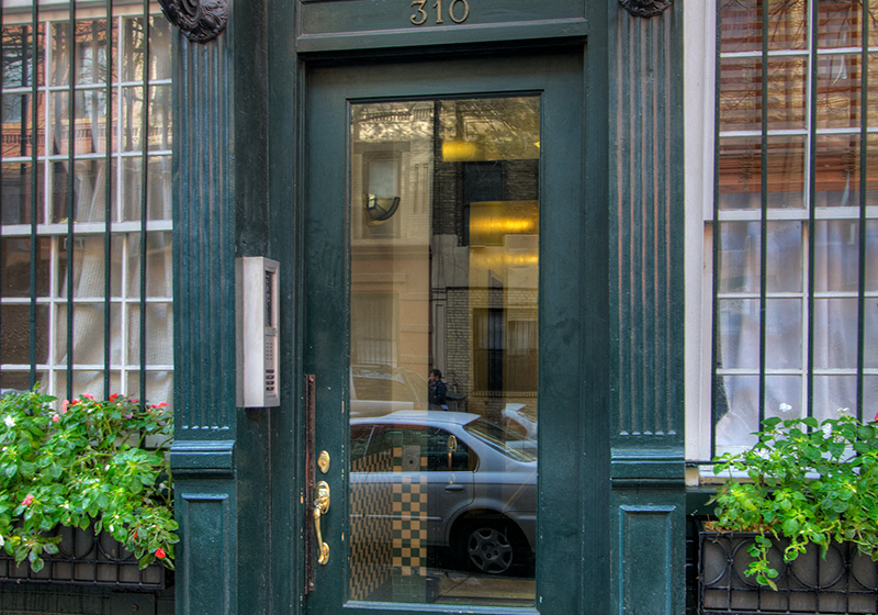 a car reflected in the window of a green door
