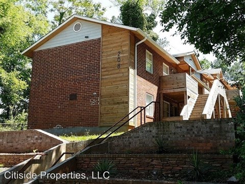 a brick house with a wooden porch and stairs