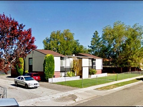 A white car is parked in front of a house.