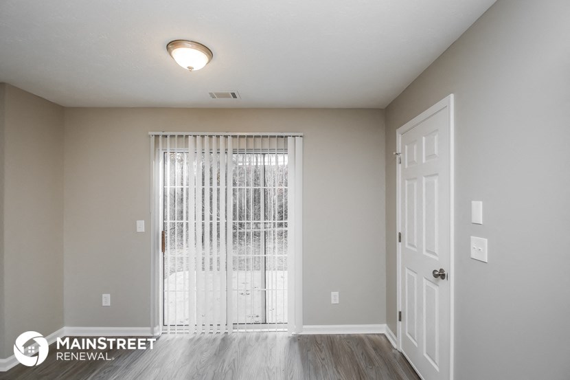 the spacious living room of an apartment with a door to the patio