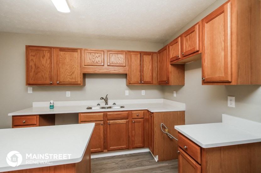 a kitchen with wooden cabinets and white counters and a sink