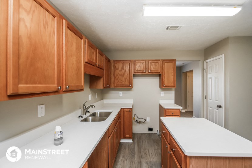 a kitchen with wooden cabinets and white counter tops and a sink
